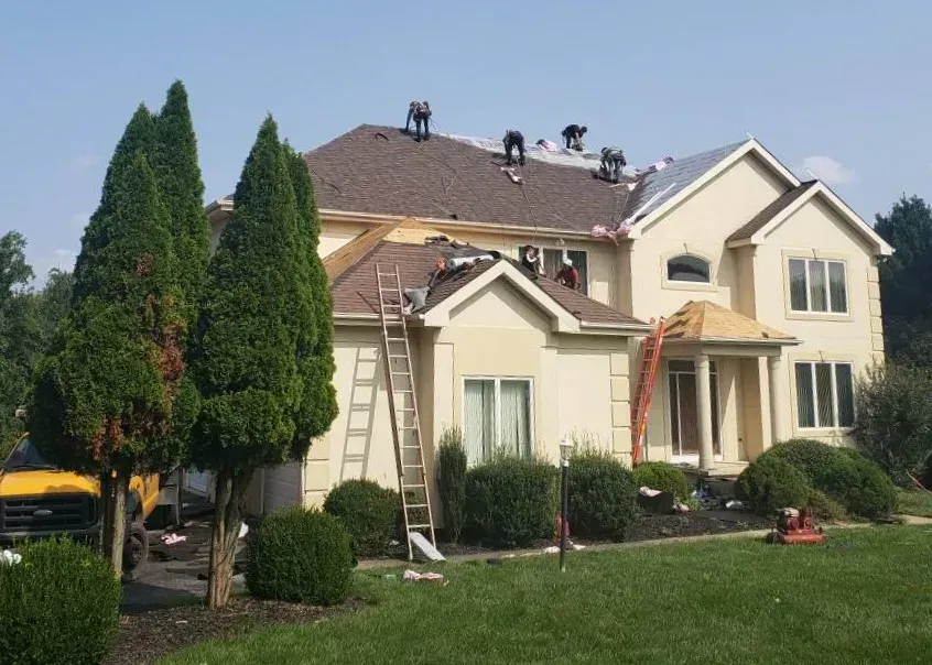 Roofing crew re-shingling the roof of a two-story home